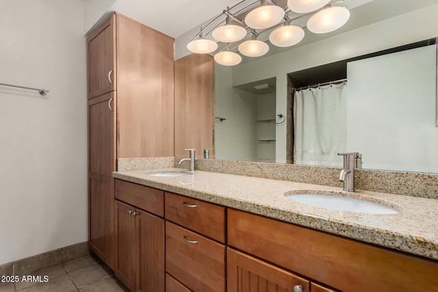 bathroom with tile patterned flooring, a sink, baseboards, and double vanity