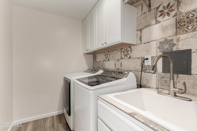 laundry area with wood finished floors, baseboards, washer and clothes dryer, a sink, and cabinet space