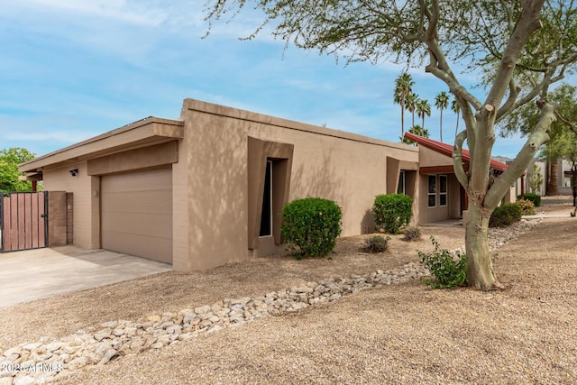view of front facade with a gate, stucco siding, and driveway
