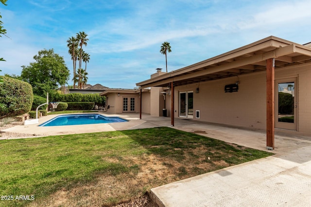 pool with french doors, a yard, and a patio area