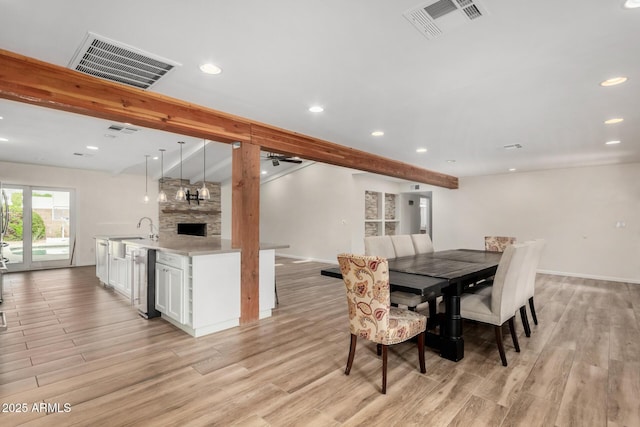 dining area featuring visible vents, light wood-style flooring, and beam ceiling
