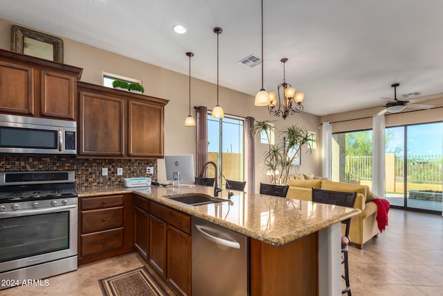 kitchen featuring decorative backsplash, appliances with stainless steel finishes, a kitchen breakfast bar, sink, and hanging light fixtures