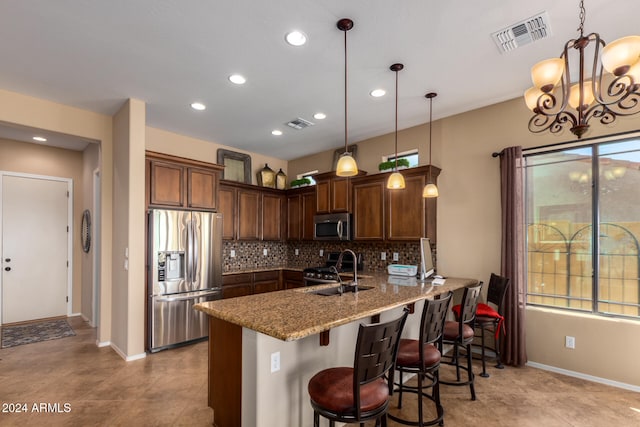 kitchen featuring light stone countertops, backsplash, kitchen peninsula, decorative light fixtures, and appliances with stainless steel finishes