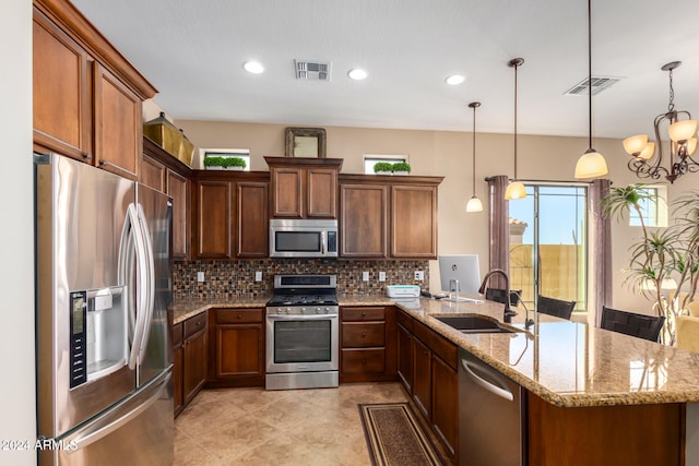 kitchen featuring pendant lighting, backsplash, sink, light stone countertops, and appliances with stainless steel finishes