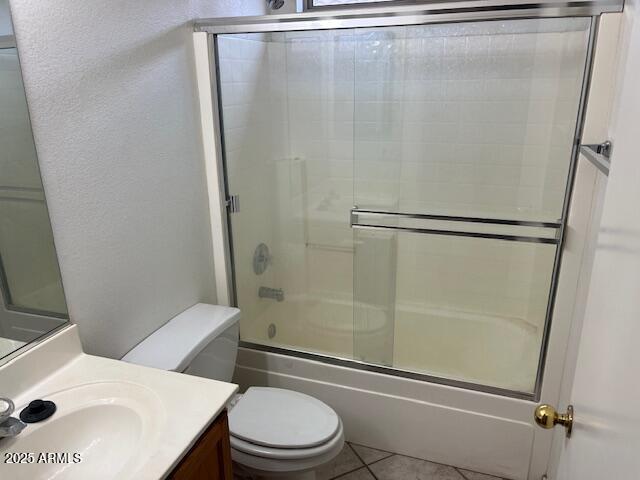 full bathroom featuring tile patterned flooring, vanity, toilet, and bath / shower combo with glass door