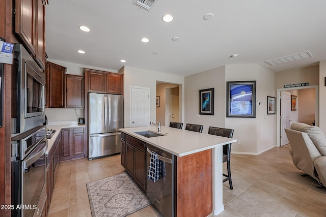 kitchen with visible vents, a breakfast bar area, stainless steel appliances, light countertops, and a sink