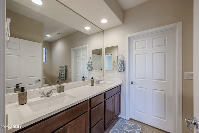 full bathroom with recessed lighting, a sink, toilet, and double vanity