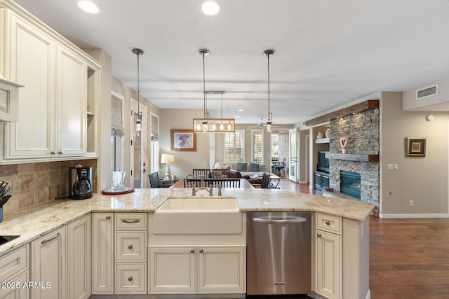 kitchen featuring visible vents, a sink, open floor plan, a peninsula, and dishwasher