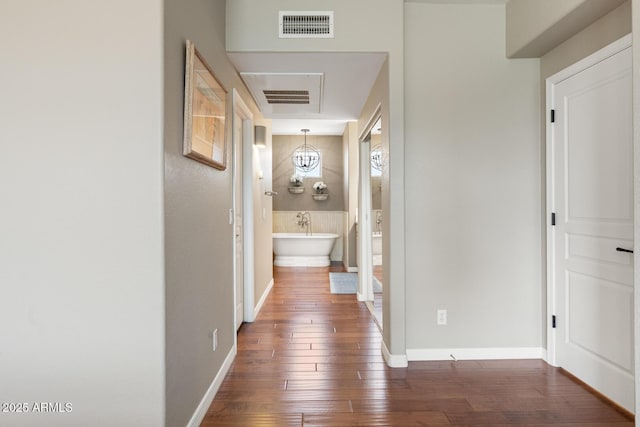 corridor featuring visible vents, baseboards, and hardwood / wood-style flooring