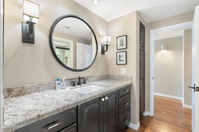 bathroom featuring visible vents, vanity, baseboards, and wood finished floors