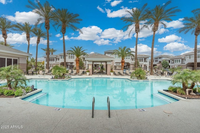 community pool featuring a patio, fence, and a residential view