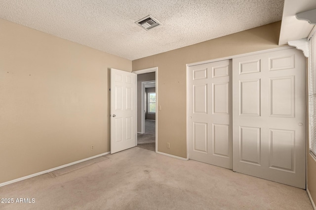 unfurnished bedroom with visible vents, baseboards, carpet floors, a closet, and a textured ceiling