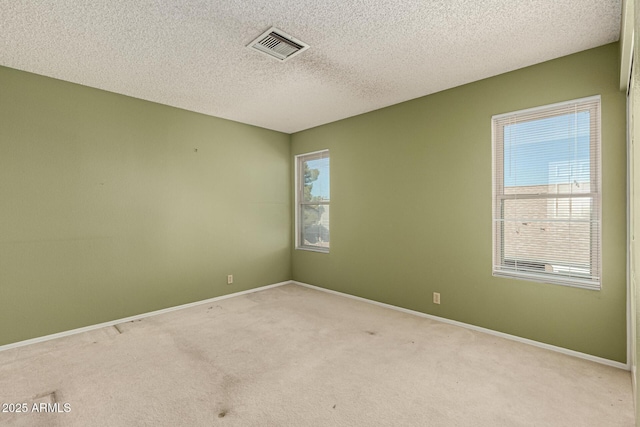 unfurnished room featuring visible vents, baseboards, light colored carpet, and a textured ceiling