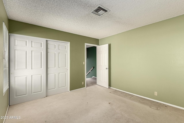 unfurnished bedroom with a closet, visible vents, carpet floors, and a textured ceiling