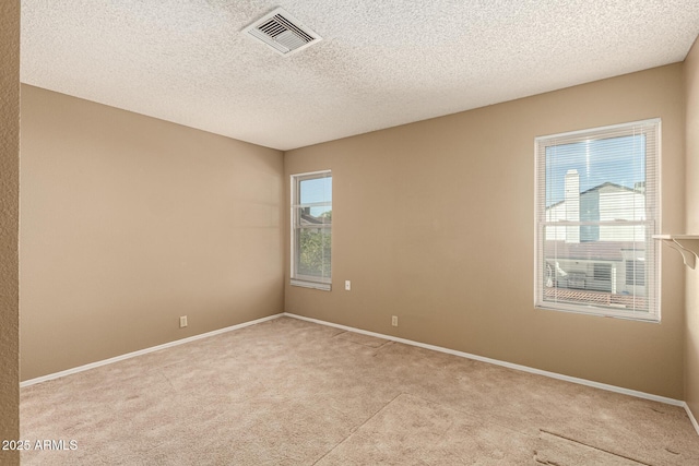 empty room with a textured ceiling, carpet, visible vents, and baseboards