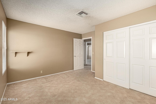 unfurnished bedroom with visible vents, a textured ceiling, a closet, carpet flooring, and baseboards