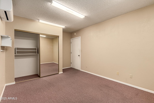 unfurnished bedroom with an AC wall unit, carpet, a closet, and baseboards