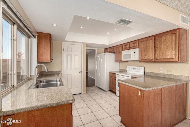 kitchen with a sink, a tray ceiling, white appliances, and visible vents