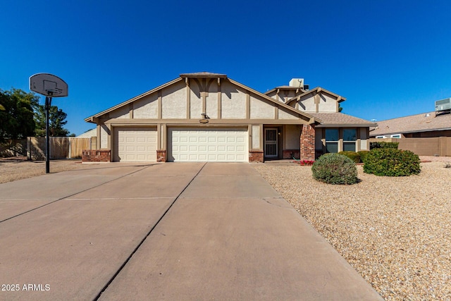 view of front of property with stucco siding, driveway, fence, an attached garage, and brick siding