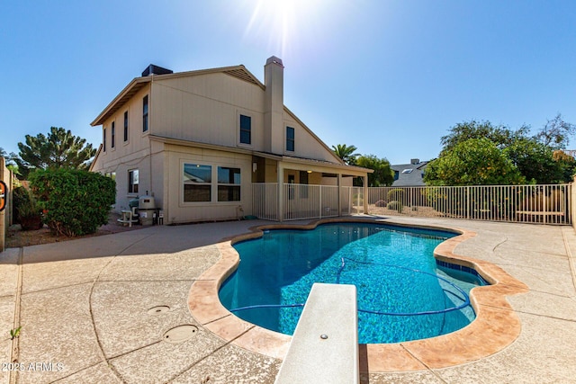 view of pool featuring a diving board, a fenced in pool, a patio, and fence