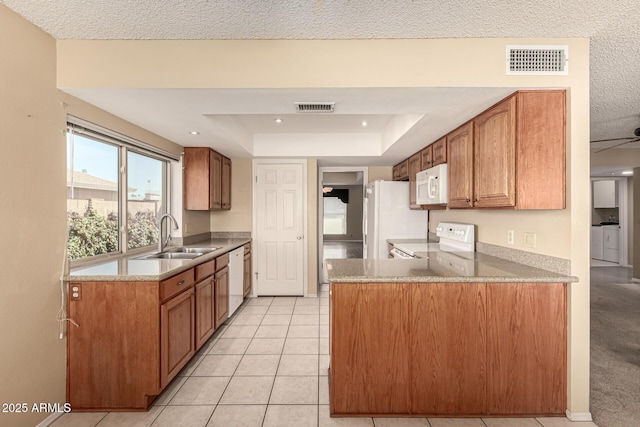 kitchen featuring white appliances, visible vents, a raised ceiling, and a sink