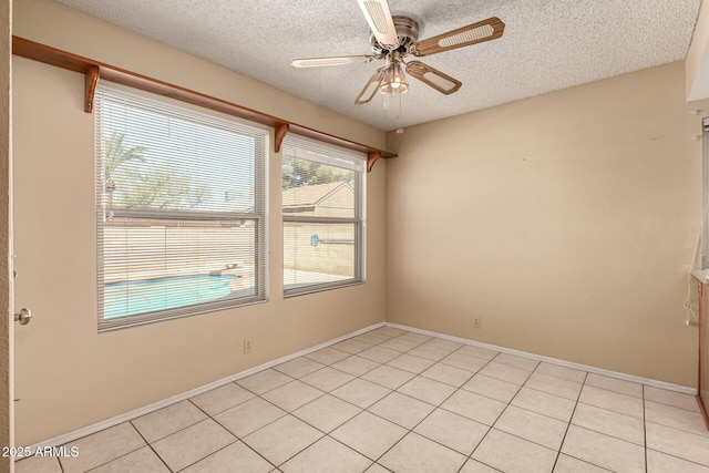 spare room with light tile patterned floors, a ceiling fan, and a textured ceiling