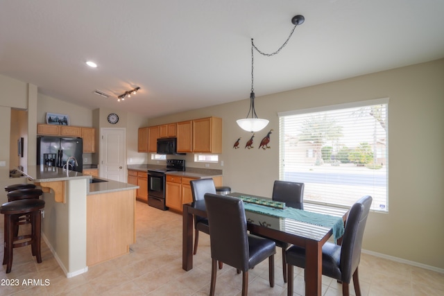 kitchen featuring lofted ceiling, sink, a kitchen island with sink, black appliances, and decorative light fixtures