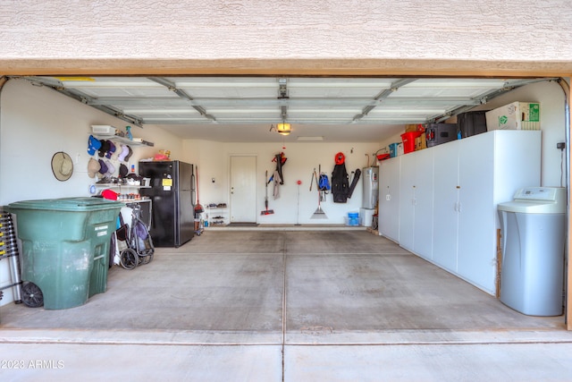 garage with a garage door opener, electric water heater, and black refrigerator