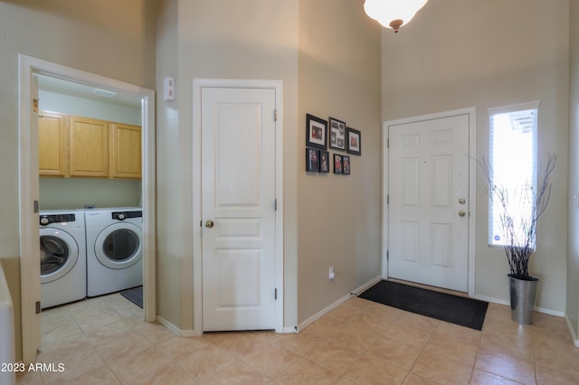 laundry area featuring washer and clothes dryer, cabinets, a high ceiling, and light tile patterned flooring