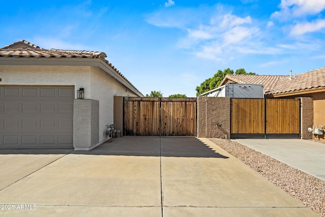 6935 W Monte Lindo St, Glendale, AZ 85310 - view of home's exterior with a gate, stucco siding, a tile roof, and an attached garage