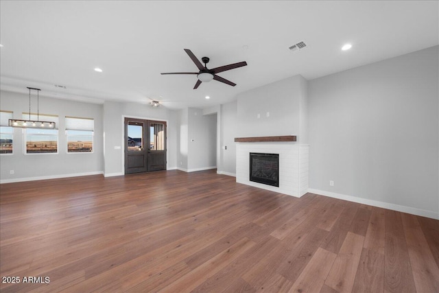 unfurnished living room featuring hardwood / wood-style floors, a brick fireplace, and ceiling fan