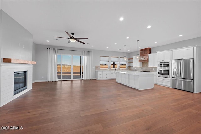 kitchen with white cabinets, a fireplace, decorative light fixtures, a kitchen island, and stainless steel appliances