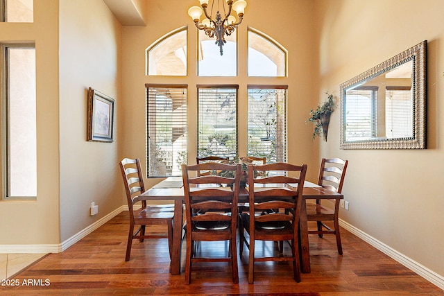 dining area with dark hardwood / wood-style floors, a chandelier, and a towering ceiling