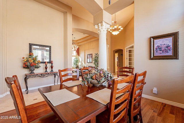 dining space featuring hardwood / wood-style flooring, a towering ceiling, and a notable chandelier