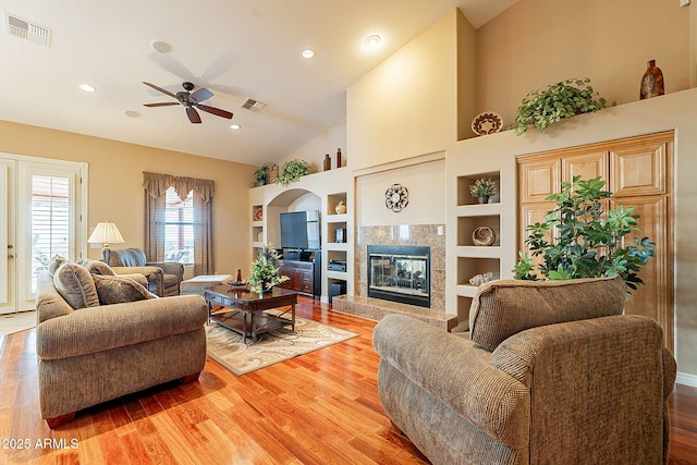 living room featuring ceiling fan, wood-type flooring, a premium fireplace, and built in features