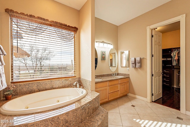 bathroom featuring tiled tub, vanity, and tile patterned floors