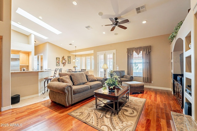 living room with lofted ceiling with skylight, hardwood / wood-style floors, and ceiling fan