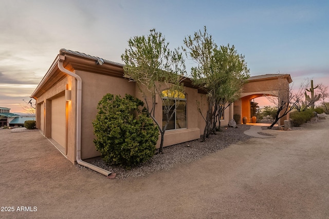 property exterior at dusk featuring a garage and central AC