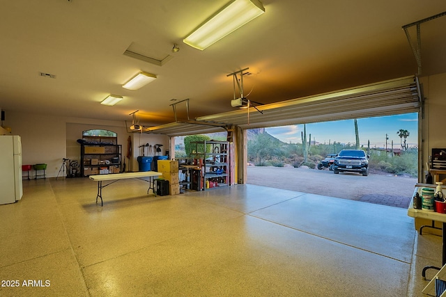 garage with a garage door opener and white fridge