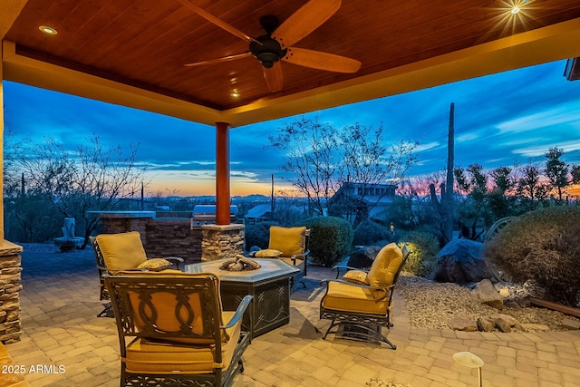 patio terrace at dusk with ceiling fan and a fire pit