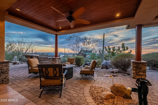 patio terrace at dusk featuring ceiling fan and exterior kitchen