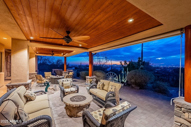 patio terrace at dusk with ceiling fan and an outdoor living space with a fire pit