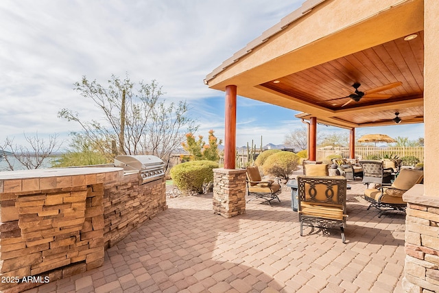 view of patio featuring a grill, ceiling fan, and an outdoor kitchen