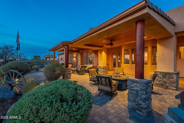 patio terrace at dusk featuring an outdoor living space with a fire pit and ceiling fan