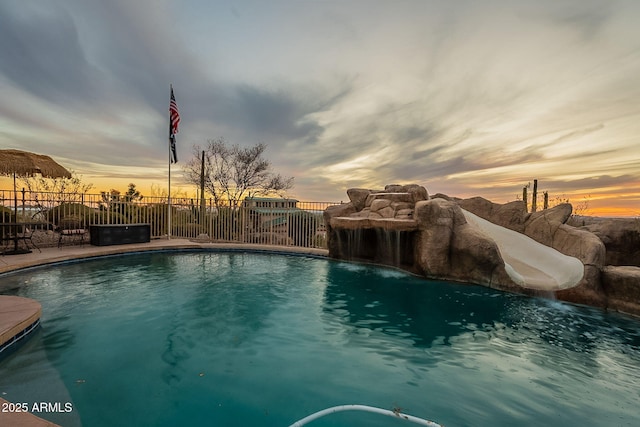 pool at dusk featuring pool water feature