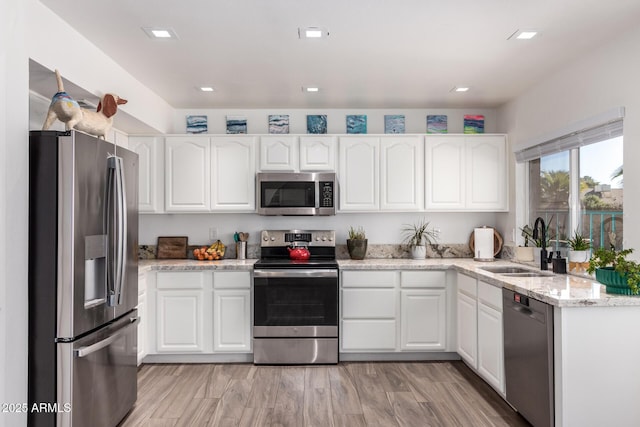 kitchen with light stone countertops, white cabinetry, appliances with stainless steel finishes, and sink