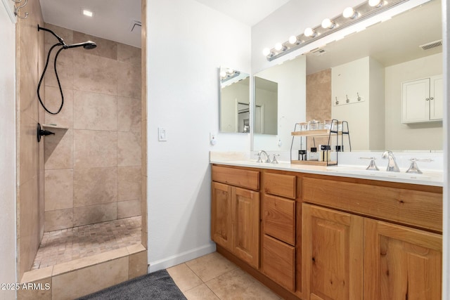 bathroom featuring tiled shower, vanity, and tile patterned flooring