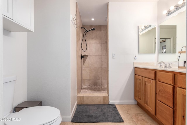 bathroom with vanity, toilet, tile patterned flooring, and a tile shower