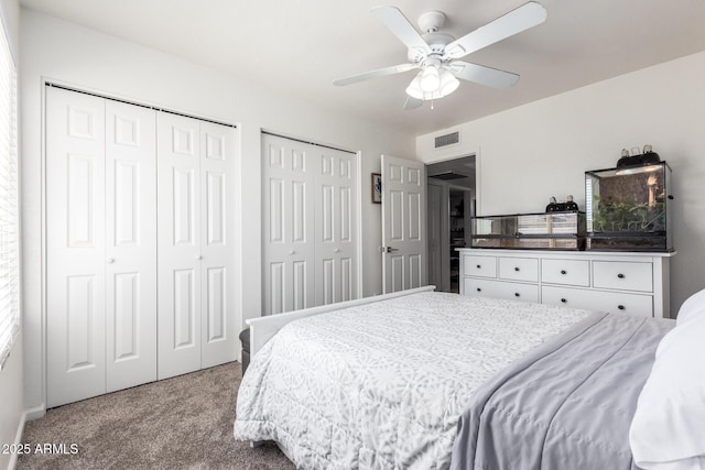 carpeted bedroom featuring multiple closets and ceiling fan