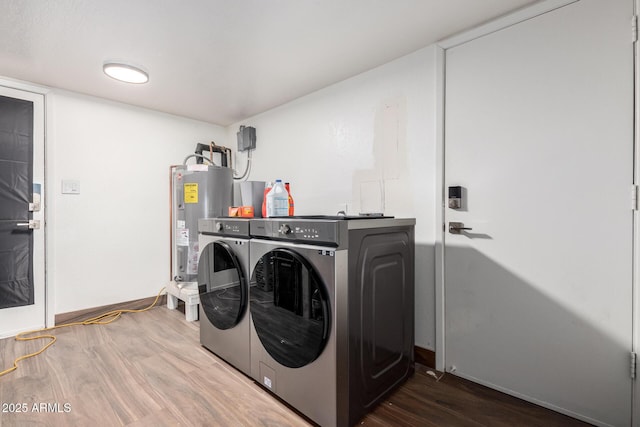 clothes washing area with hardwood / wood-style flooring, separate washer and dryer, and electric water heater